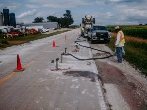 A crew of workers performs a mudjacking job on a county highway.