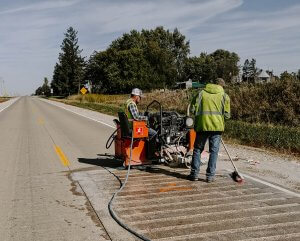 Two crew members work together to install a rumble strip panel.