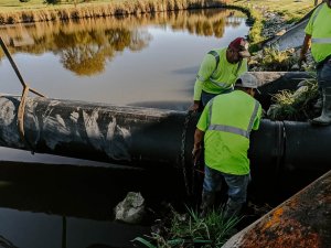 A team of Denco crew members work together to insert a slipliner into a culvert.